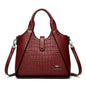 Red handbag with crocodile texture on a white background