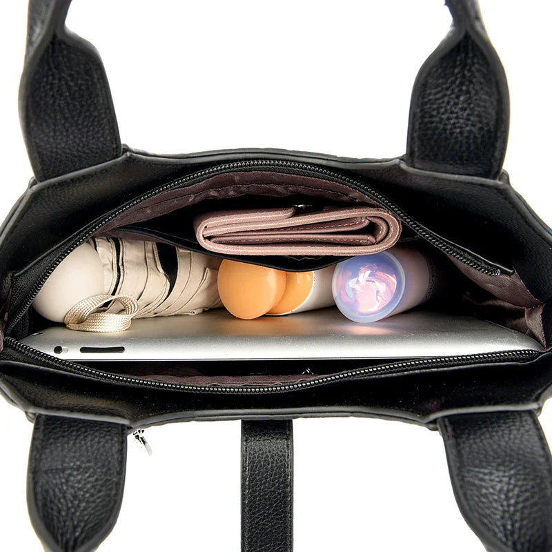 Black handbag with items including a laptop, notebooks, and a bottle.