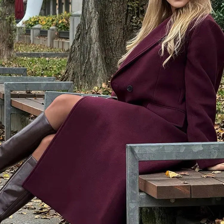 Woman in a burgundy coat sitting on a bench outdoors