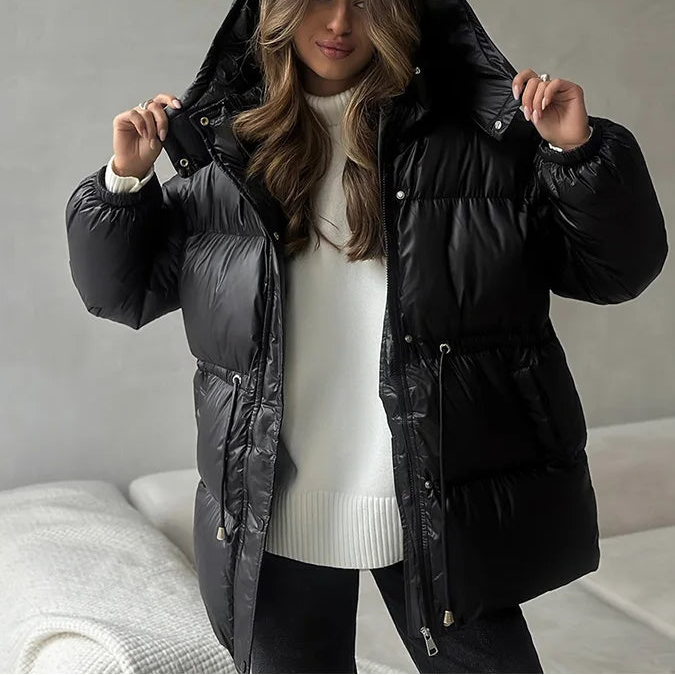 Woman wearing a black puffer jacket in a neutral setting