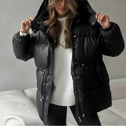Woman wearing a black puffer jacket in a neutral setting