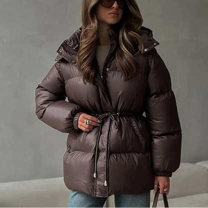 Woman wearing a brown puffer jacket against a gray background