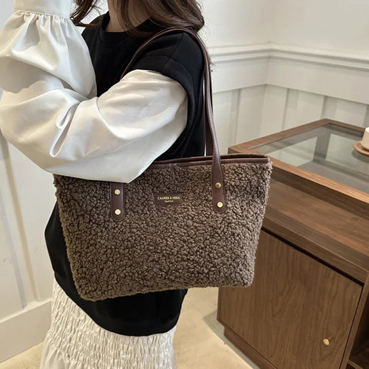 Person holding a brown textured tote bag indoors