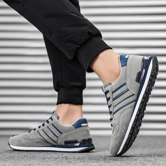 Gray sneakers with blue accents worn by a person against a metallic background