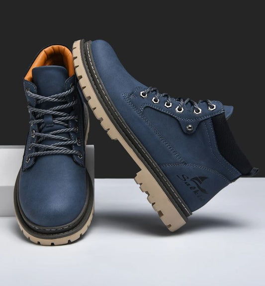 Pair of blue leather boots with brown soles on a white background