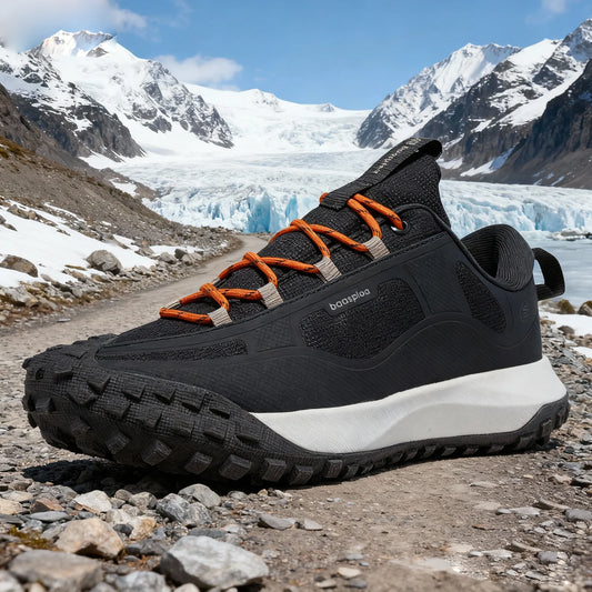 Black hiking shoe with orange laces on a mountain path