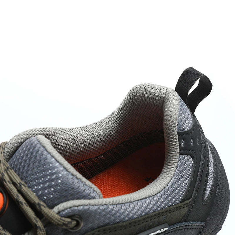 Close-up of a gray and black shoe with orange lining on a white background