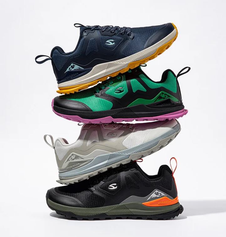 Stack of four different colored athletic shoes on a light gray background