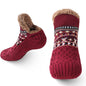 Red slipper socks with patterned sole and brown fuzzy lining on a white background