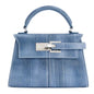 Blue denim handbag with silver hardware on a white background