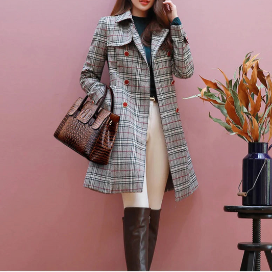 Woman wearing a plaid coat with a brown handbag against a pink background