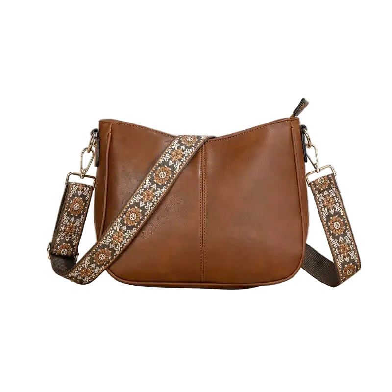 Brown leather handbag with floral strap on a white background